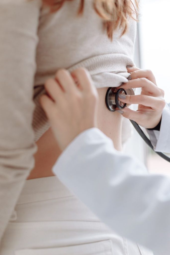 Close-up of doctor using stethoscope on patients back during medical examination.